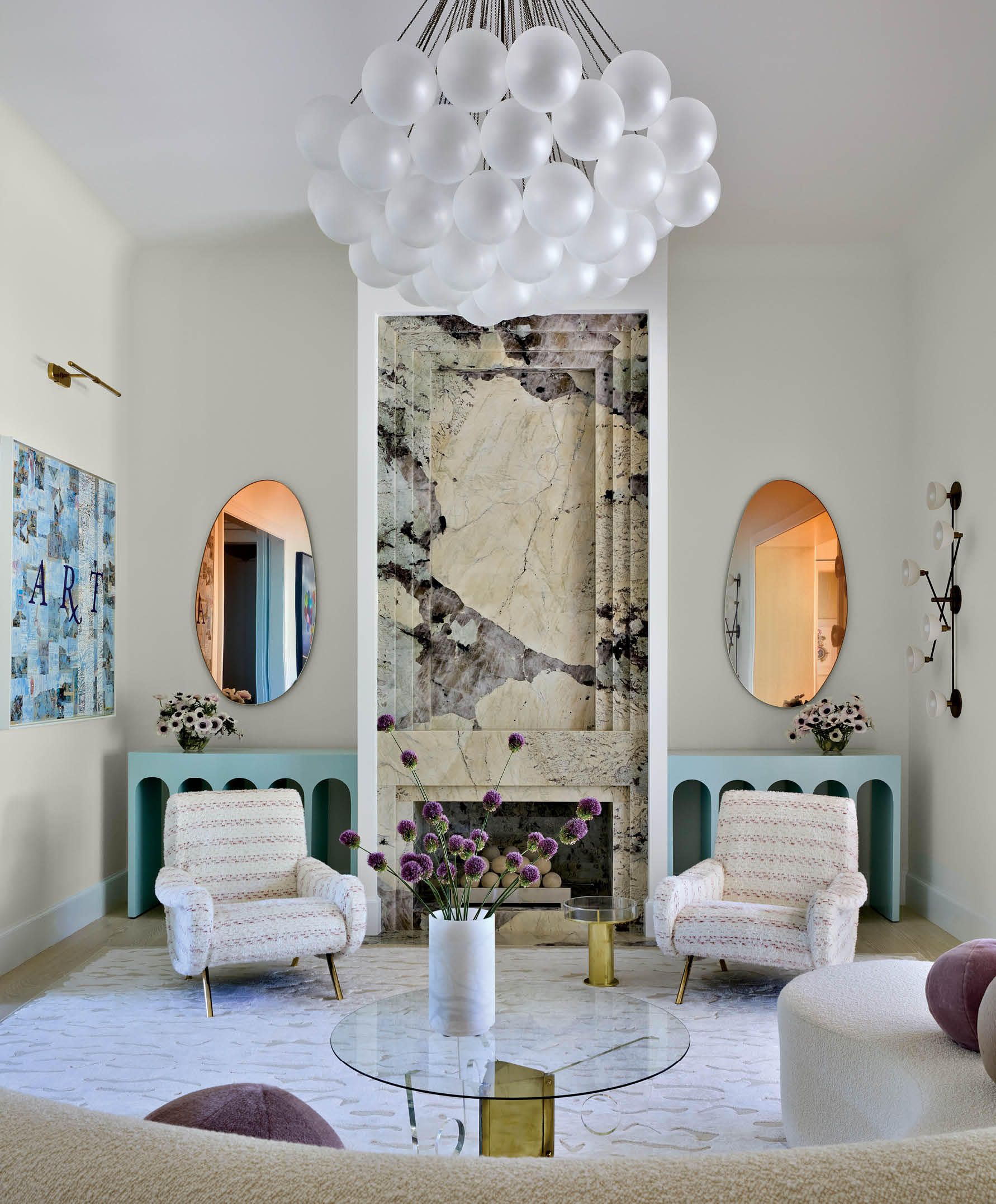 a cloud pendant crowns this modern great room with a tall stone fireplace flanked by oval mirrors